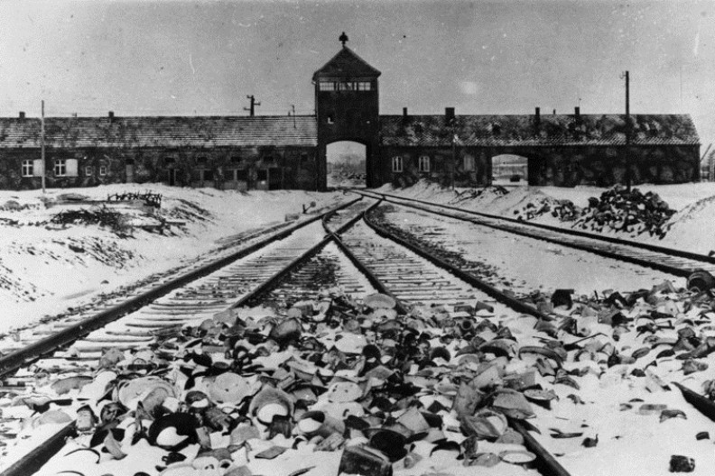 Ogrom zbrodni Niemców i wszystkich zwiedzionych przez nazistowską ideologię wciąż budzi przerażenie.  Tylko zadośćuczynienie pokrzywdzonym może być uznane za próbę rozliczenia się z tą straszną przeszłością. Na zdjęciu tory kolejowe, wartownia i brama główna obozu Auschwitz II (Birkenau), widok z rampy wewnątrz obozu, 1945 r. fot. autorstwa Bundesarchiv, B 285 Bild-04413 / Stanislaw Mucha / CC-BY-SA 3.0, CC BY-SA 3.0 de, https://commons.wikimedia.org/w/index.php?curid=5337694