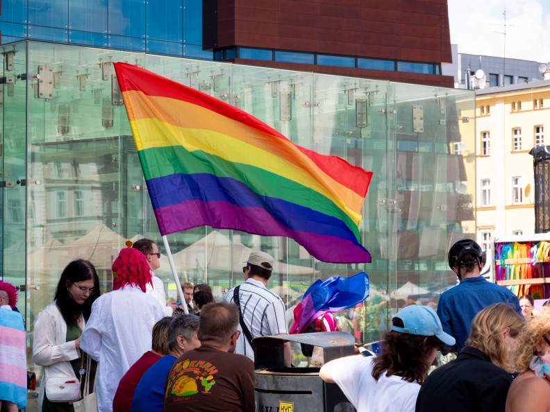 Grupa os&oacute;b z tęczową flagą LGBT. Fot. Pexels